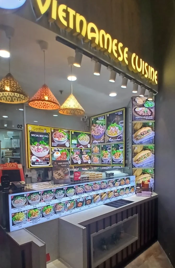 Modern F&B storefront featuring yellow 3D boxup signage and bright lightbox menu boards for a Vietnamese restaurant