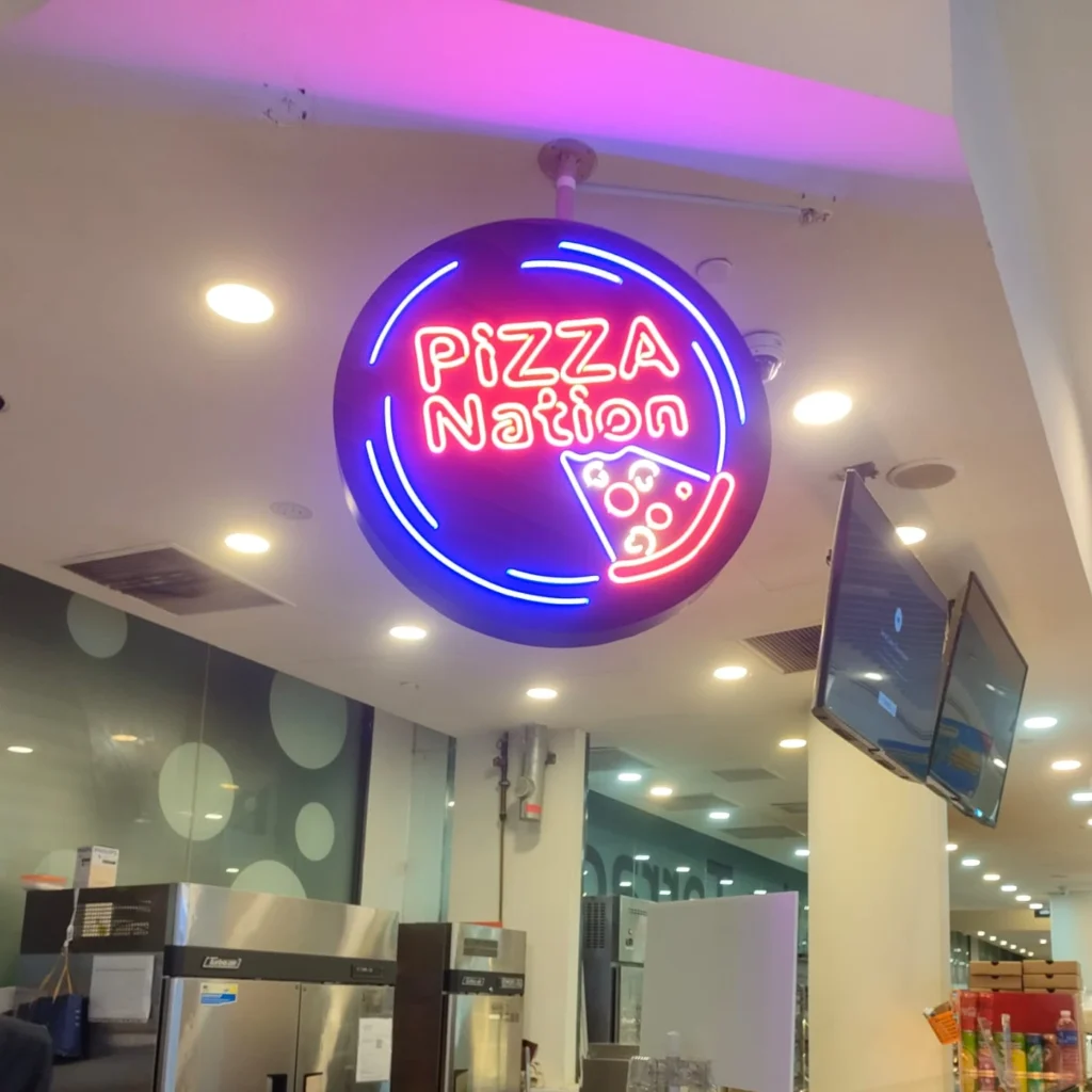 Vibrant red and blue neon signage for Pizza Nation outlet with a glowing pizza icon and border