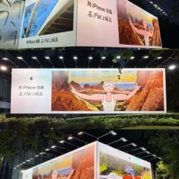 Massive illuminated outdoor corner billboard displaying high-contrast creative artwork in Singapore at night