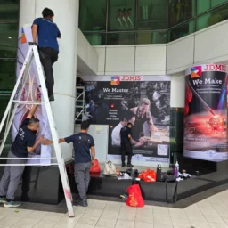 Workers are installing large-format vinyl wall wraps and pillar banners printed with promotional images