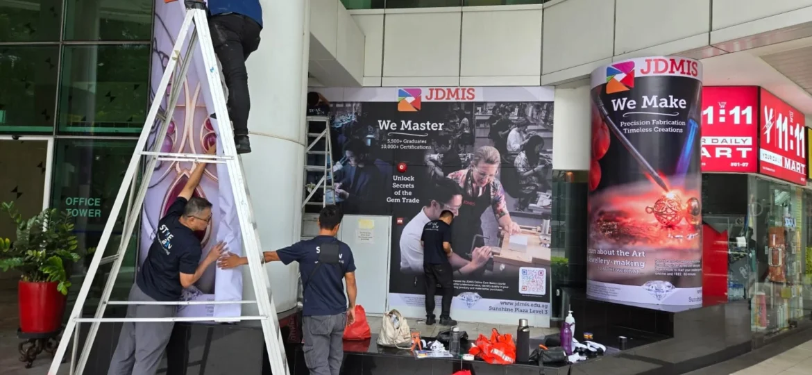 Workers are installing large-format vinyl wall wraps and pillar banners printed with promotional images