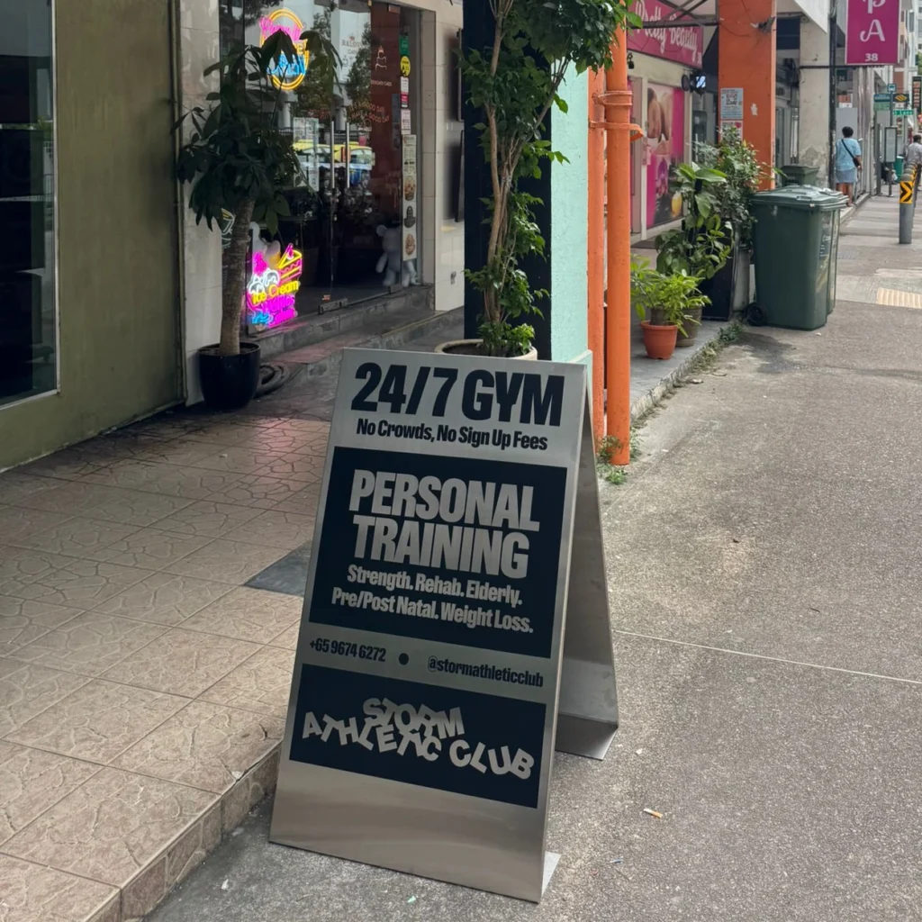 An aluminium board sign of STORM ATHLETIC CLUB in front of shopfronts