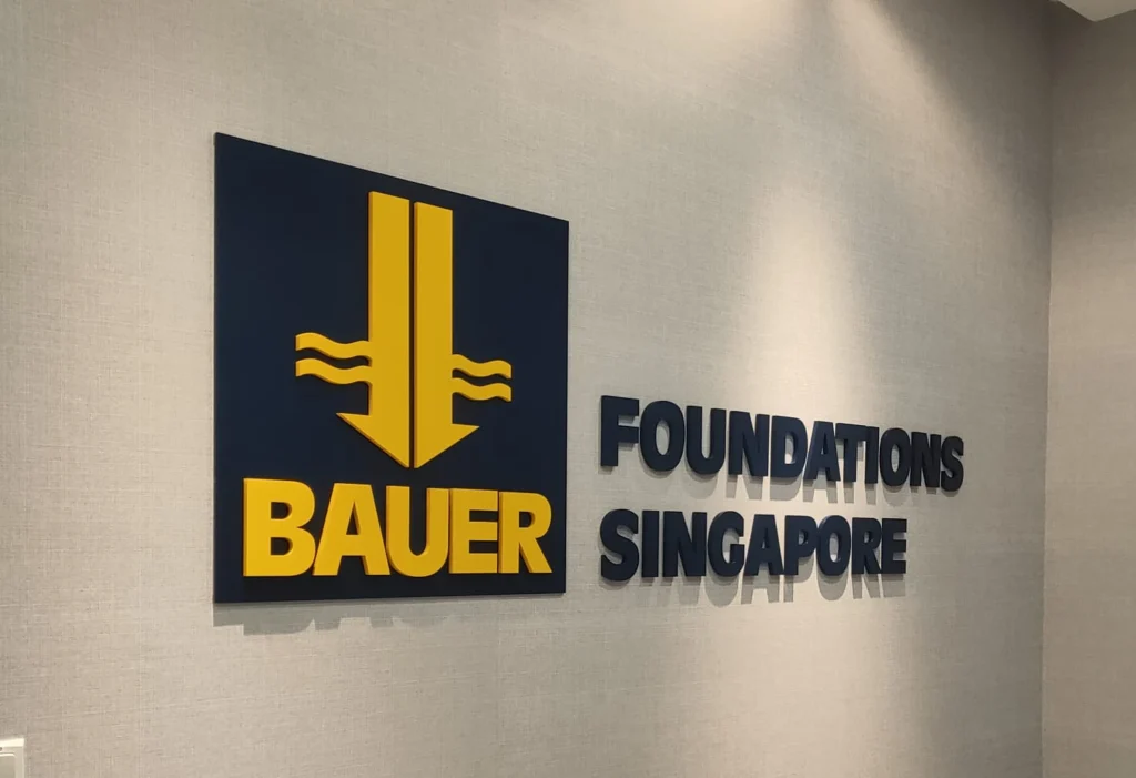 Black and yellow 3D acrylic logo letters mounted on a grey textured office wall