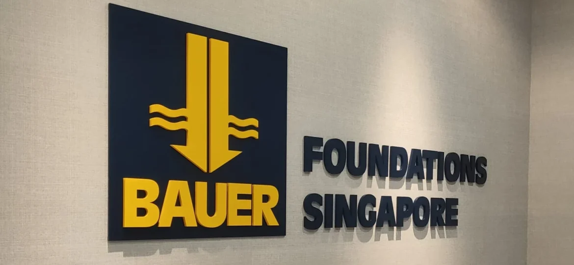 Black and yellow 3D acrylic logo letters mounted on a grey textured office wall