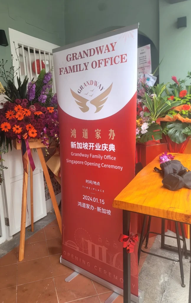 Roll-up banner for Grandway Family Office Singapore opening ceremony placed alongside floral stands.